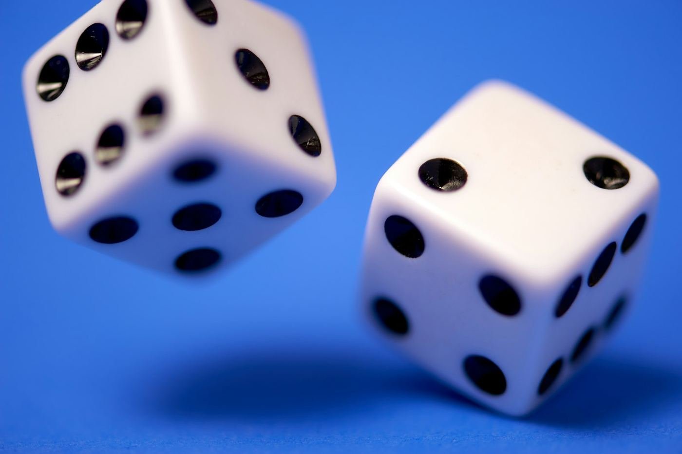 Two white dice tumbling against a blue background