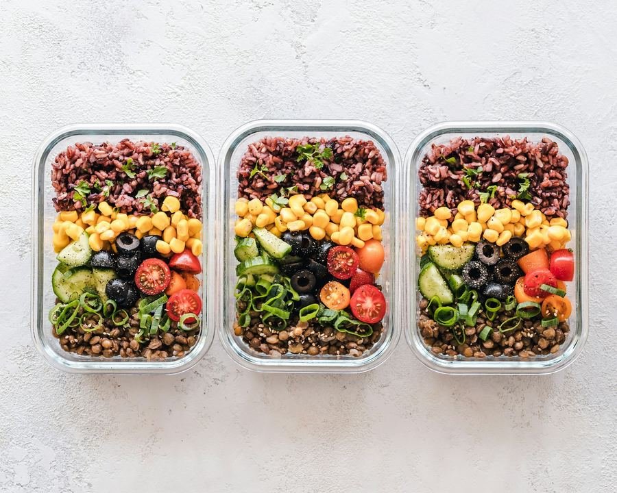 Three meal-prep containers with grains, chickpeas and fresh vegetables