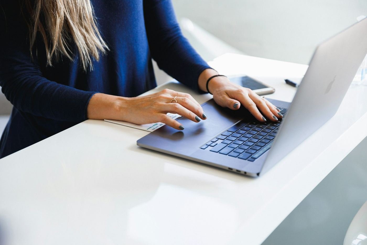 Person typing a message on a laptop at a white desk
