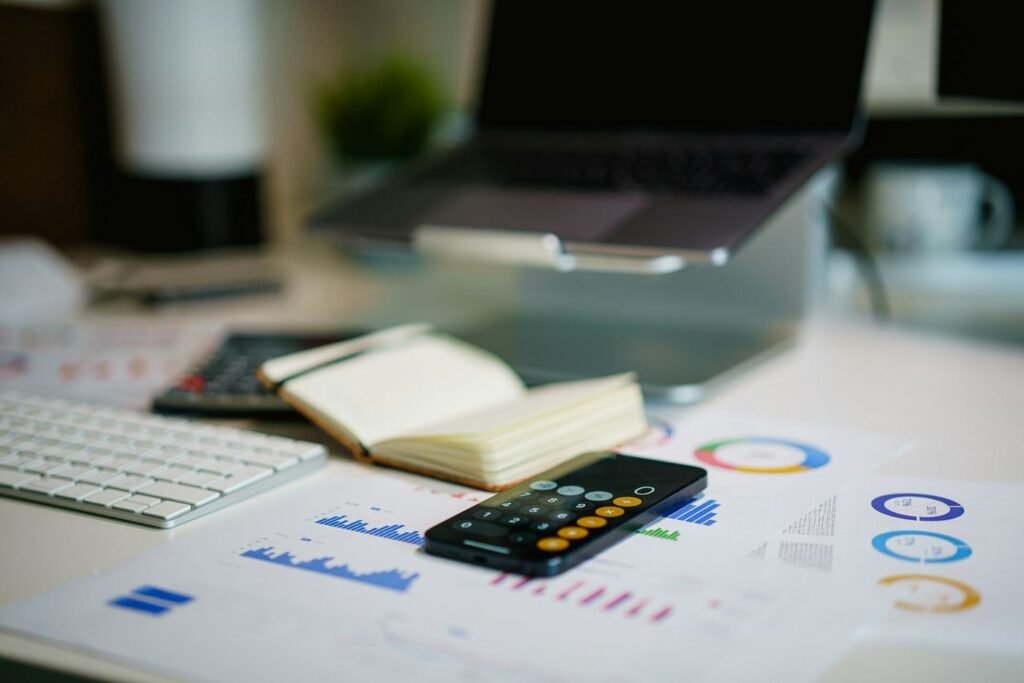 Desk with a notebook, phone calculator, keyboard and printed charts